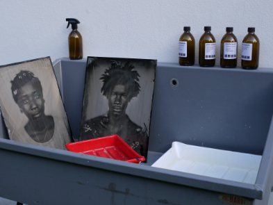 Darkroom setup with tank, trays, photographs, and chemicals.